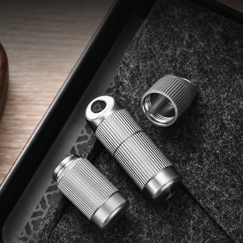 Disassembled cylindrical titanium storage capsule with threaded sections on dark felt