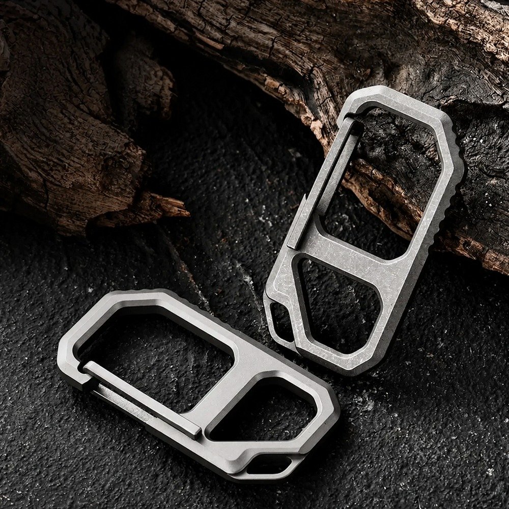 Two titanium carabiner bottle opener keychains on dark stone and wood